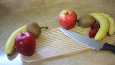 Slow-Motion-shot-of-a-variety-of-fruits-on-a-cutting-board-with-a-knife-laying-next-to-them