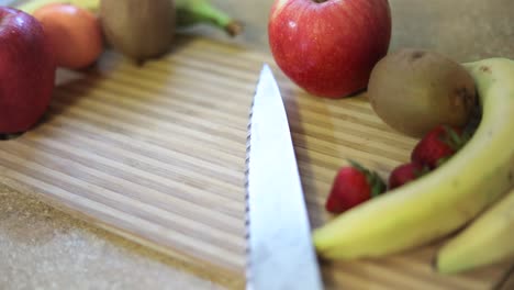 Slow-Motion-shot-of-a-variety-of-fruits-on-a-cutting-board-with-a-knife-laying-next-to-them