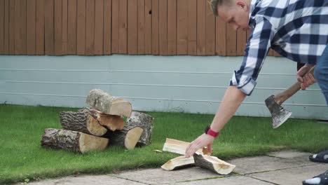 Young-man-with-blue-checked-shirt-is-chopping-wood-in-smaller-pieces