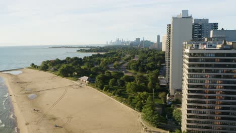 Drone-Flies-close-to-High-Rise-Condominium-with-beach,-Lake-Shore-Drive,-and-Chicago-Skyline-in-background-[4k