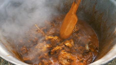 slow-motion-of-cooking-lamb-stew-with-wooden-spoon-in-big-cauldron