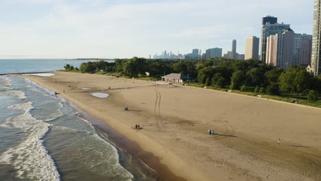 Aerial-shot-of-peaceful-beach-in-Chicago's-north-neighborhoods-with-Chicago-skyline-in-background-[4k