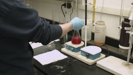 Dolly-shot-of-chemist-running-a-lab-experiment-with-colored-liquid-in-a-flask