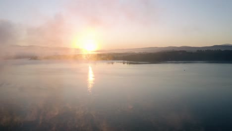 Sunrise-at-a-lake-with-amazing-colours,-a-mist-floating-over-a-water-surface