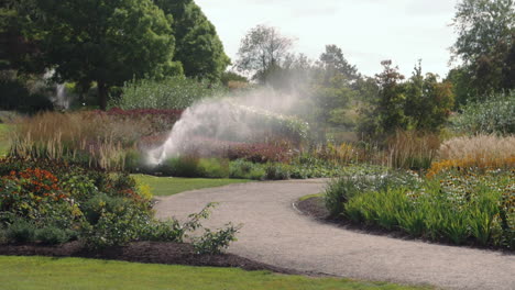 Sprinkler-system-watering-gardens-of-flowers-Part-2---handheld-slow-motion