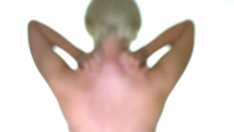 A-female-rubbing-massaging-the-back-of-her-neck,-with-a-gaussian-blur-effect,-on-a-seamless-white-studio-background