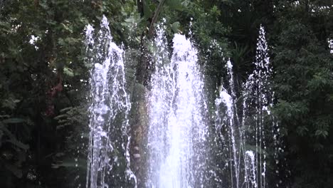 Wasserbrunnen-In-Zeitlupe-Gegen-Grüne-Bäume-Und-Natur,-Aufgenommen-In-Marbella,-Malaga,-Spanien-Mit-120-Fps
