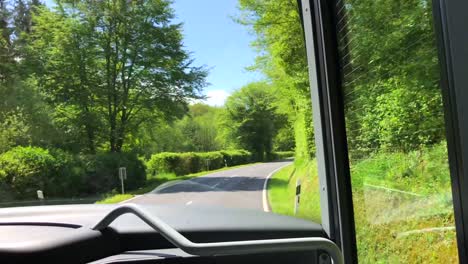 Passangers-point-of-view-sitting-in-a-bus-and-driving-forward-through-a-green-forest-in-Luxembourg
