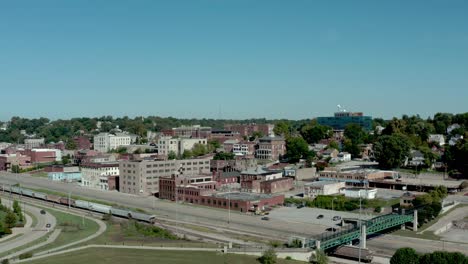 Drone-footage-of-downtown-Alton,-Illinois-buildings,-train,-bridge,-riverfront-and-carnival