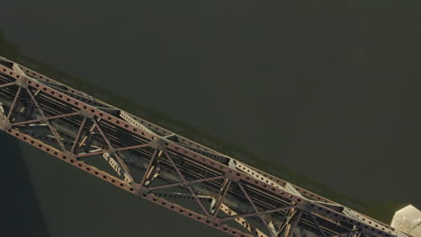 Oben-Aufsteigende-Drohnenaufnahme-Einer-Eisenbahnbrücke,-Die-Einen-Fluss-überquert,-Aufgenommen-Bei-Sonnenaufgang