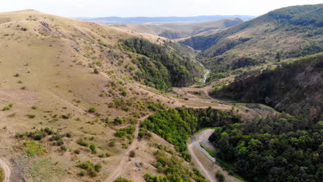 Drone-flying-over-a-small-canyon-separating-forest-and-grass-land