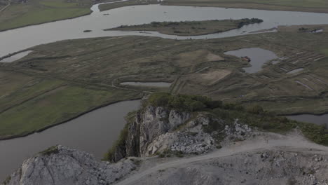 Parallax-aerial-shot-of-the-riverbed-down-below-an-abandoned-quarry-on-top-of-the-mountain-summit-in-the-evening,-Russia