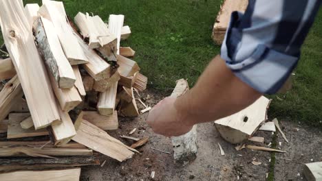 Young-man-is-chopping-wood-in-smaller-pieces-and-putting-it-aside