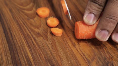 Close-up-of-hands-Chopping-Carrot-on-wooden-board---Cutting-vegetables-into-small-pieces-with-knife