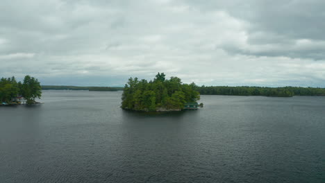 Descending-drone-view-of-Gem-Island-in-the-middle-of-Lake-Muskoka-on-a-grey,-cool-day
