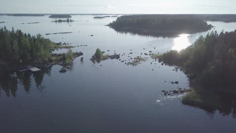 Aerial,-descending,-drone-shot,-tilting-towards-a-motorboat,-driving-between-small-islands,-tranquil-sea,-in-the-Kvarken-archipelago,-on-a-calm-and-sunny,-summer-day,-in-Finland---Flat-color-profile