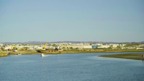 Sport-boat-passing-by-at-river-mouth-during-dawn-at-Tavira-Portugal