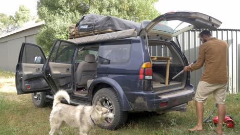 Man-with-dog-vacuuming-inside-Of-dirty-Suv-cleaning-vehicle-after-road-trip