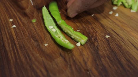 handheld-shot---Close-up-of-hands-Chopping-green-chilli-on-wooden-board---Cutting-veggies-into-small-pieces-with-knife---concept-of-healthy-food