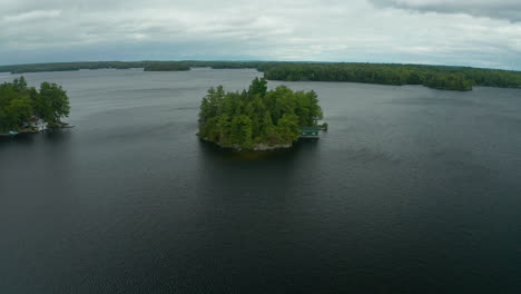 Aerial-view-flying-over-a-small-isolated-island-with-a-cottage-on-it-in-the-middle-of-a-lake