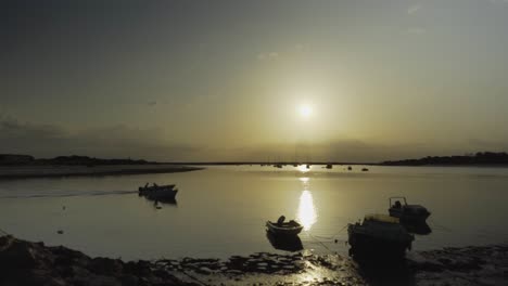 Flusssonne-Morgens-Mit-Vorbeifahrendem-Fischerboot-Und-Silhouettenbooten-Im-Hintergrund-In-Tavira-Portugal