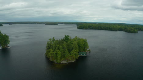 Drone-shot-flying-counter-clockwise-around-a-small-island-in-the-middle-of-Muskoka-lake-on-a-dreary-day