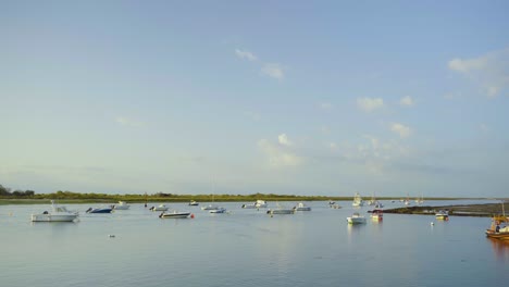 River-mouth-floating-anchored-sport-and-fishing-boats-at-sunrise-at-Tavira-Portugal-4K