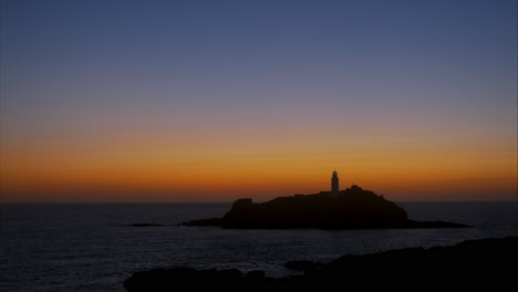 Golden-warm-sunset-at-Godrevy-Lighthouse-with-orange,-ochre-and-blue-colours,-panning-shot