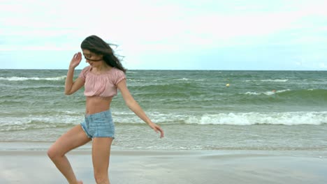 A-beautiful-young-woman-dressed-casually-and-showing-beautiful-dance-moves-at-the-sea-shore