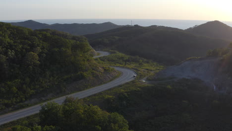 Serpentine-road-in-the-mountains-with-car-parked-on-the-road-side-in-the-sunset