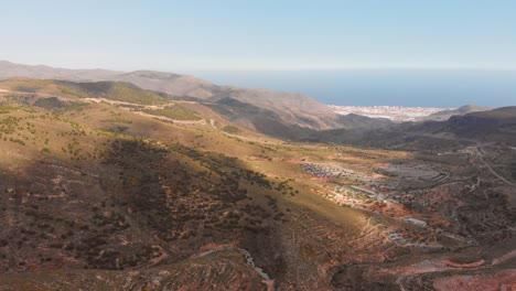 The-mountains-near-Almeria-in-the-south-of-Spain-with-in-the-background-the-greenhouses,-Aerial-shot