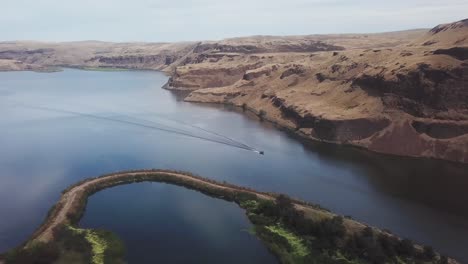 Aerial,-panoramic-view-following-a-speedboat-down-the-Palouse-River-and-into-the-Snake-River-in-the-Scablands-of-Eastern-Washington-state