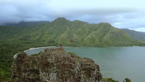 Drone-shot-circling-a-pair-of-hikers-standing-on-top-of-the-cliffs-on-the-Crouching-Lion-hike-on-Oahu,-Hawaii
