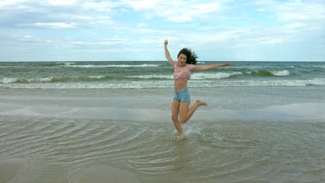Brunette-dancer-jumping-and-dancing-in-slow-motion-on-the-sea-shore