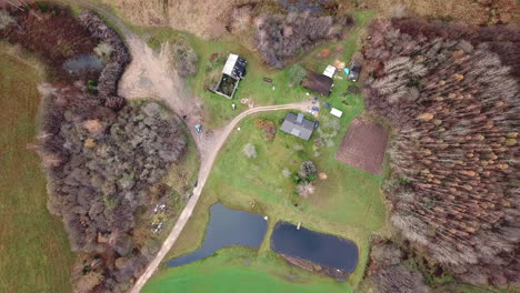 Aerial-DESCENDING-shot-footage-of-old-houses-in-rural-countryside-village-with-two-ponds-next-to-it