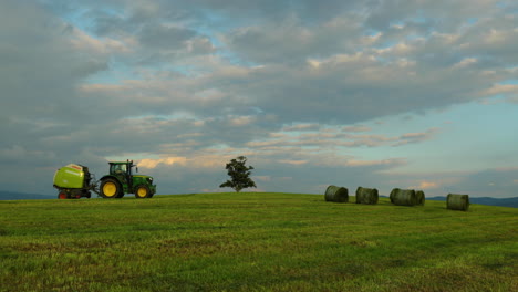 An-agricultural-machine-riding-in-the-loading-hay-on-the-ground-on-a-hill-overlooking-the-moving-clouds-and-changing-the-sunlight-into-the-shade-overlooking-the-natural-landscape-in-4k-60fps