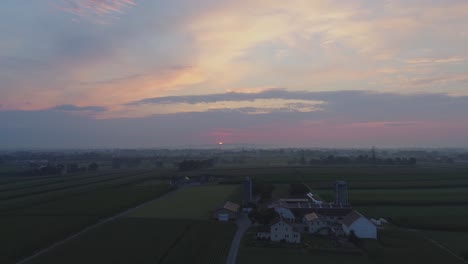 Luftaufnahme-Eines-Sonnenaufgangs-über-Amish-Farm-Landet-An-Einem-Nebligen-Sommermorgen