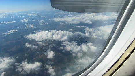 Through-airplane-window-view,-aircraft-window,-Hublot,-during-flight-airplane-seat-view,-aerial-clouds-and-sky-view