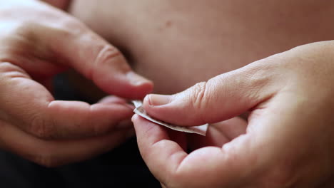 Close-up-of-cleaning-the-abdomen-with-a-wet-hygiene-wipe-in-preparation-to-self-apply-medicine-through-a-medical-needle-pen-injecting-the-substance-in-a-fatty-area-of-the-belly