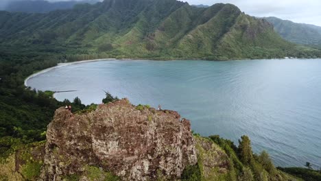 Drone-shot-flying-away-from-a-pair-of-hikers-standing-on-top-of-the-cliffs-at-the-Crouching-Lion-hike-on-Oahu,-Hawaii