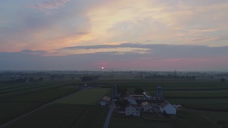 Vista-Aérea-De-Un-Amanecer-Sobre-Tierras-Agrícolas-Amish-En-Una-Brumosa-Mañana-De-Verano