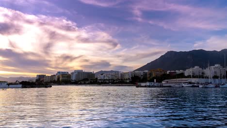 Marbella,-4k-time-lapse-of-marbella-from-marbella-fishing-port,-beautiful-view-of-moving-clouds-at-sunset-and-sailing-boats-moving-in-the-harbor