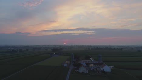 Vista-Aérea-De-Un-Amanecer-Sobre-Tierras-Agrícolas-Amish-En-Una-Brumosa-Mañana-De-Verano