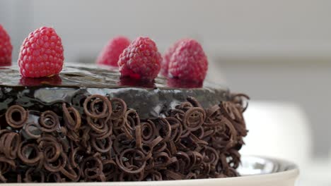 Close-up-shot-of-chocolate-cake-topped-with-raspberries-and-garnished-chocolate-spirals-rotating-counterclockwise