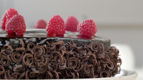 Close-up-shot-of-chocolate-cake-topped-with-raspberries-and-garnished-chocolate-spirals-rotating-clockwise