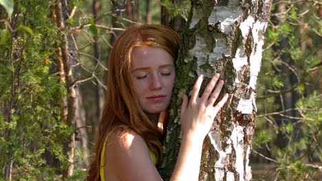Young-redhead-woman-embracing-tree-in-forest