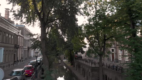 Aerial-early-morning-canal-view-of-the-Nieuwe-Gracht-in-medieval-Dutch-city-of-Utrecht-at-sunrise-rising-between-the-trees-at-the-upper-street-level