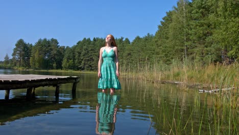 A-young-woman-standing-in-the-lake-water-alone-enjoying-the-sun-and-the-summertime-weather
