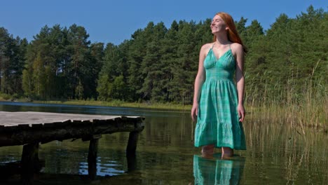 Happy-reedhead-woman-standing-in-lake-and-splashing-water-falling-next-to-her
