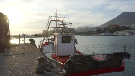 Kleines-Rotes-Und-Weißes-Fischerboot,-Das-Bei-Sonnenuntergang-Im-Fischhafen-Von-Marbella-Festgemacht-Ist,-Wunderschöne-Filmische-Aussicht-Auf-Das-Spanische-Fischerboot